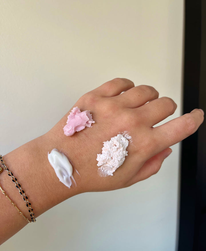 Face cream swatches on hand: white lotion and a pale pink smudge