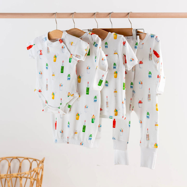Kids pajama sets hanging together, white with colorful popsicle print, matching pieces