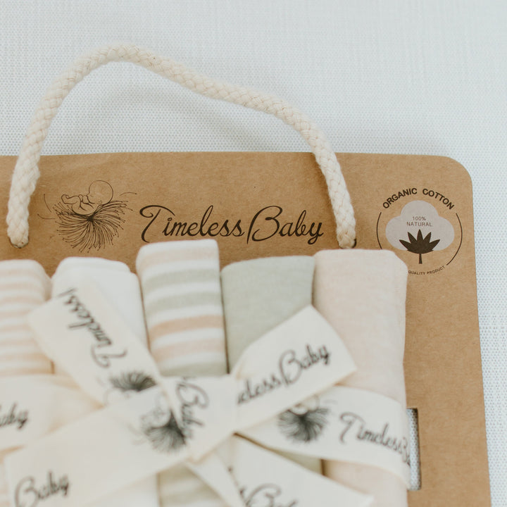 Organic cotton baby washcloths peeking from kraft gift box with brand label.