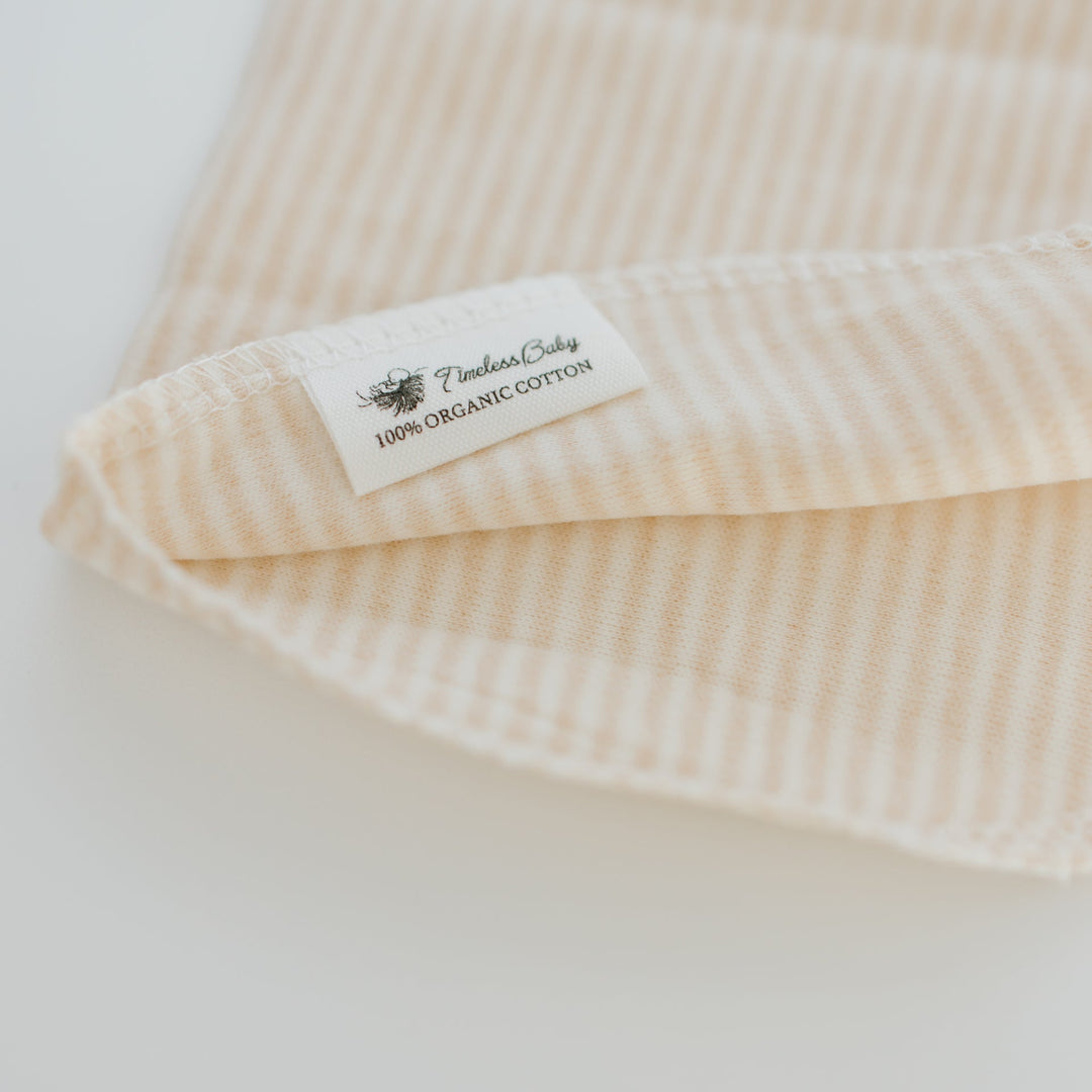 Cream striped baby washcloth with sewn-in organic cotton fabric label.