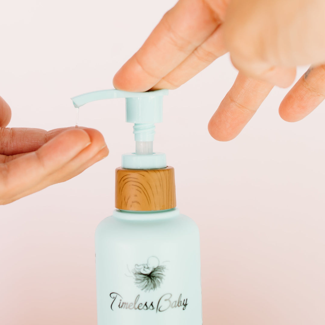 Hand pressing mint pump on light-blue hair and body wash bottle with wooden cap