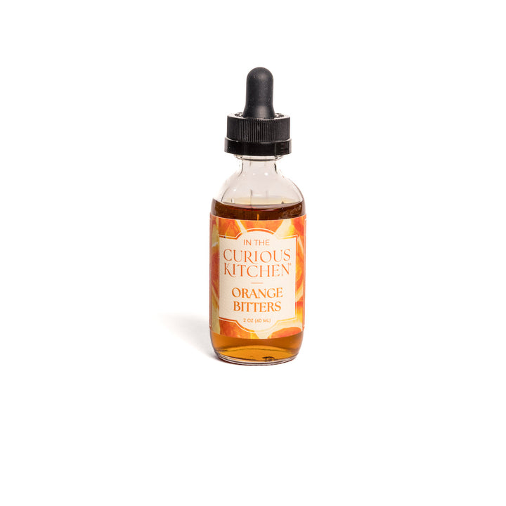 Orange bitters bottle with black dropper, amber liquid, front label visible through glass.