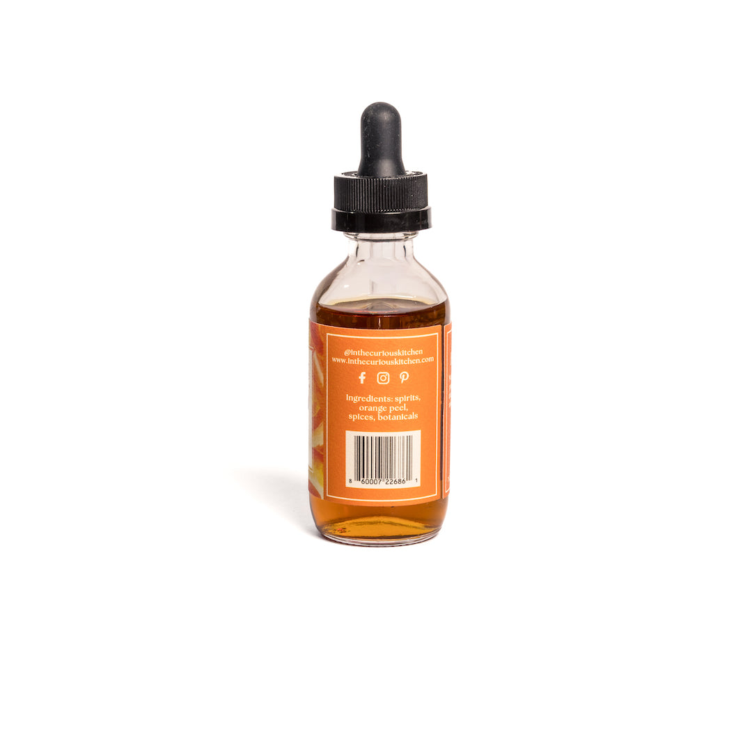 Orange bitters bottle with black dropper, amber liquid, barcode label on back.