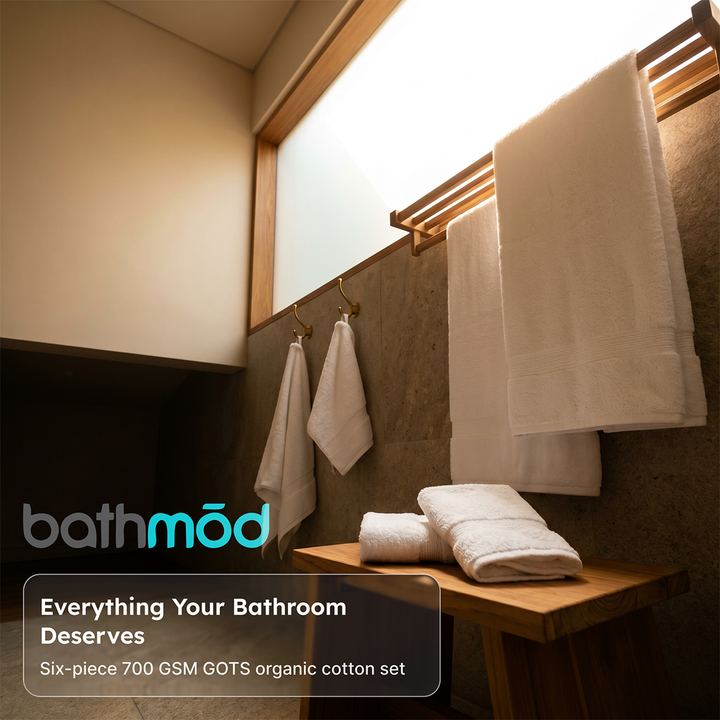 White bath towel set with two towels hanging and folded towels on wooden shelf