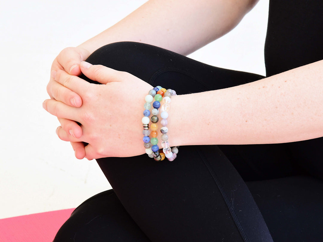 Stacked beaded bracelets on wrist with multicolor small beads and light-blue accent beads
