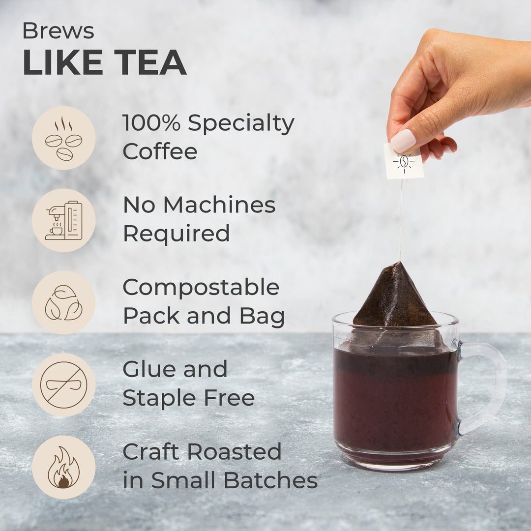 Hand holding a single-serve coffee steeped bag above a glass mug of coffee.