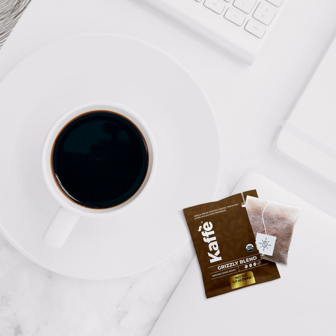 Dark coffee in white cup with Grizzly Blend steeped bag sachet