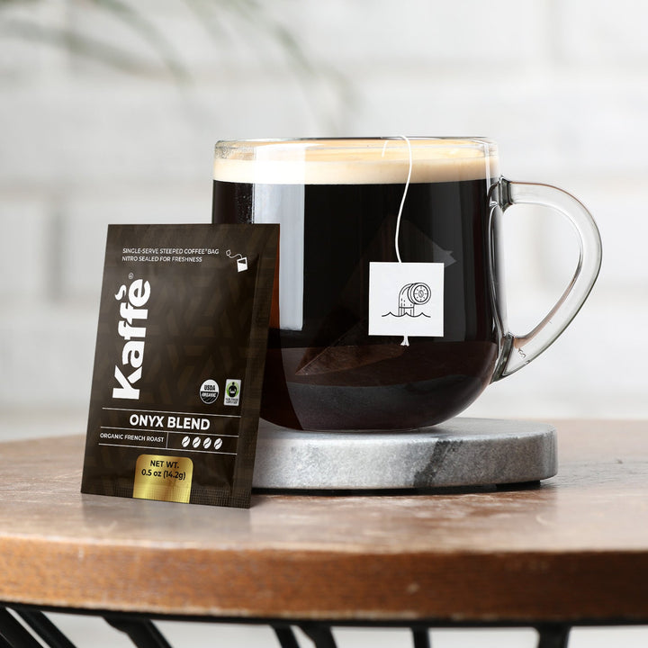 Onyx Blend coffee steeped bag beside a glass mug of dark coffee