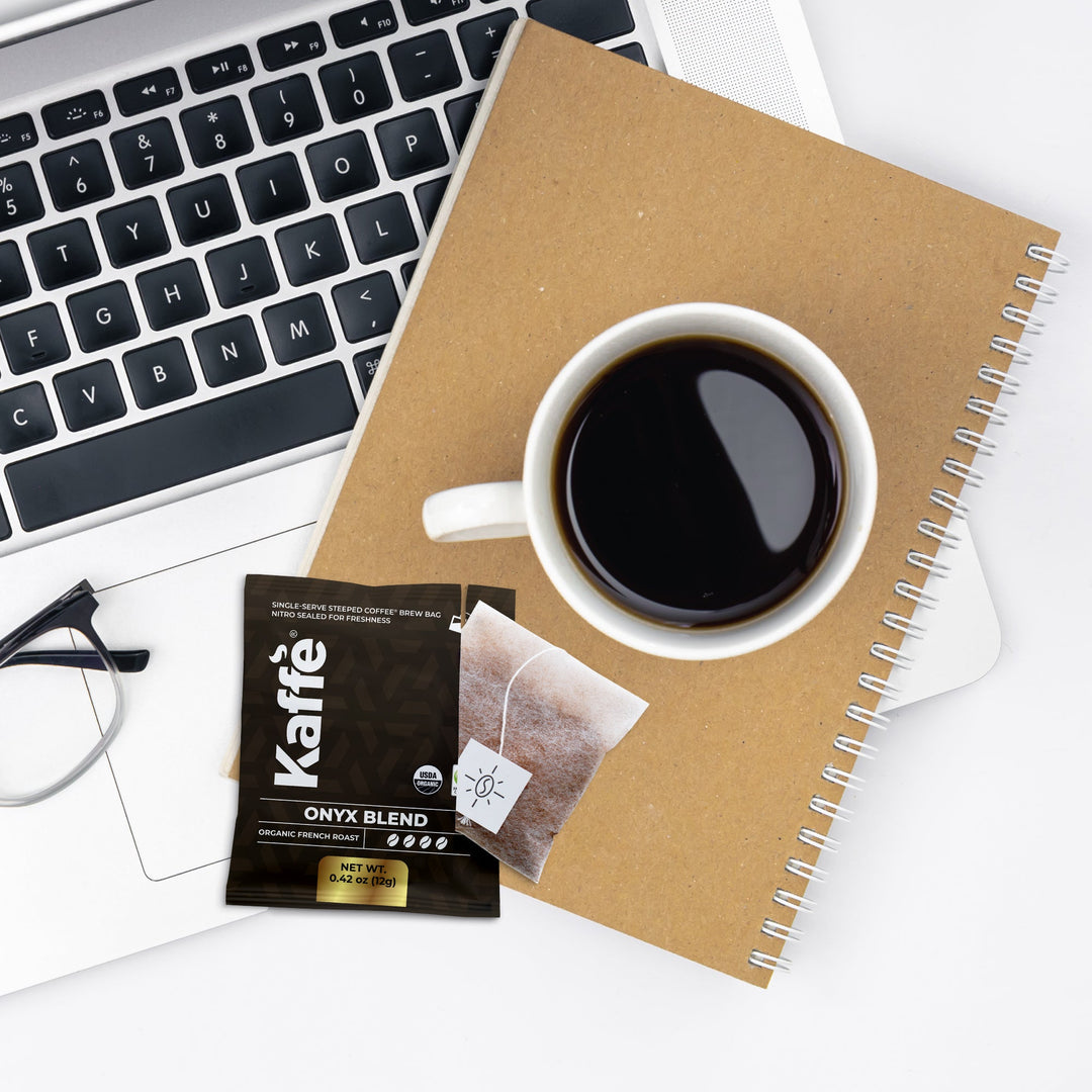 Coffee steeped bag with drawstring-style tea tag and cup of dark coffee
