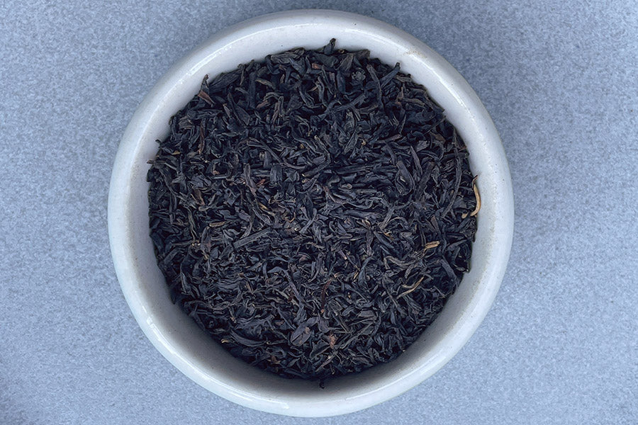 Keemun tea leaves in a white bowl, dark loose leaf tea