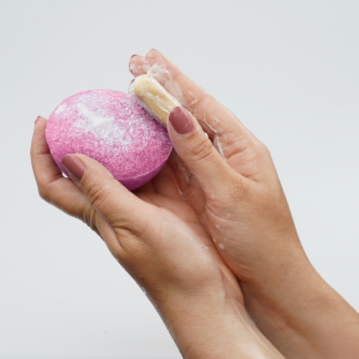 Pink konjac facial cleansing sponge in hands with light cleansing foam