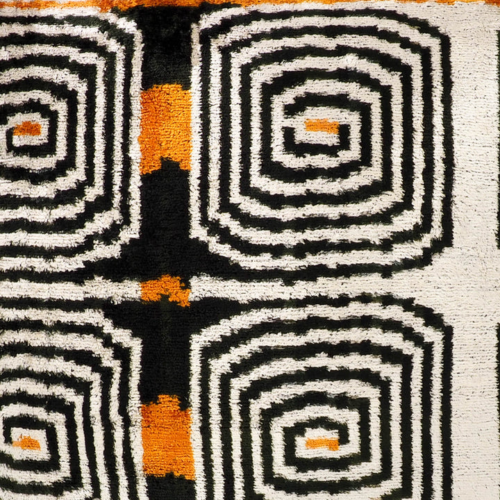 Tight close-up of labyrinth ikat velvet pattern in cream, black, and orange
