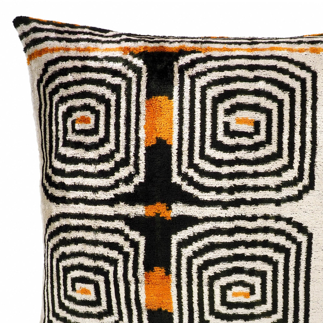 Close-up of cream and black labyrinth ikat velvet pillow pattern with orange crosses
