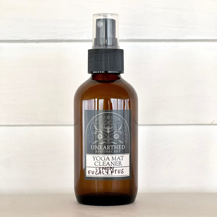 Yoga mat cleaning spray bottle with eucalyptus label, amber glass and black mist sprayer