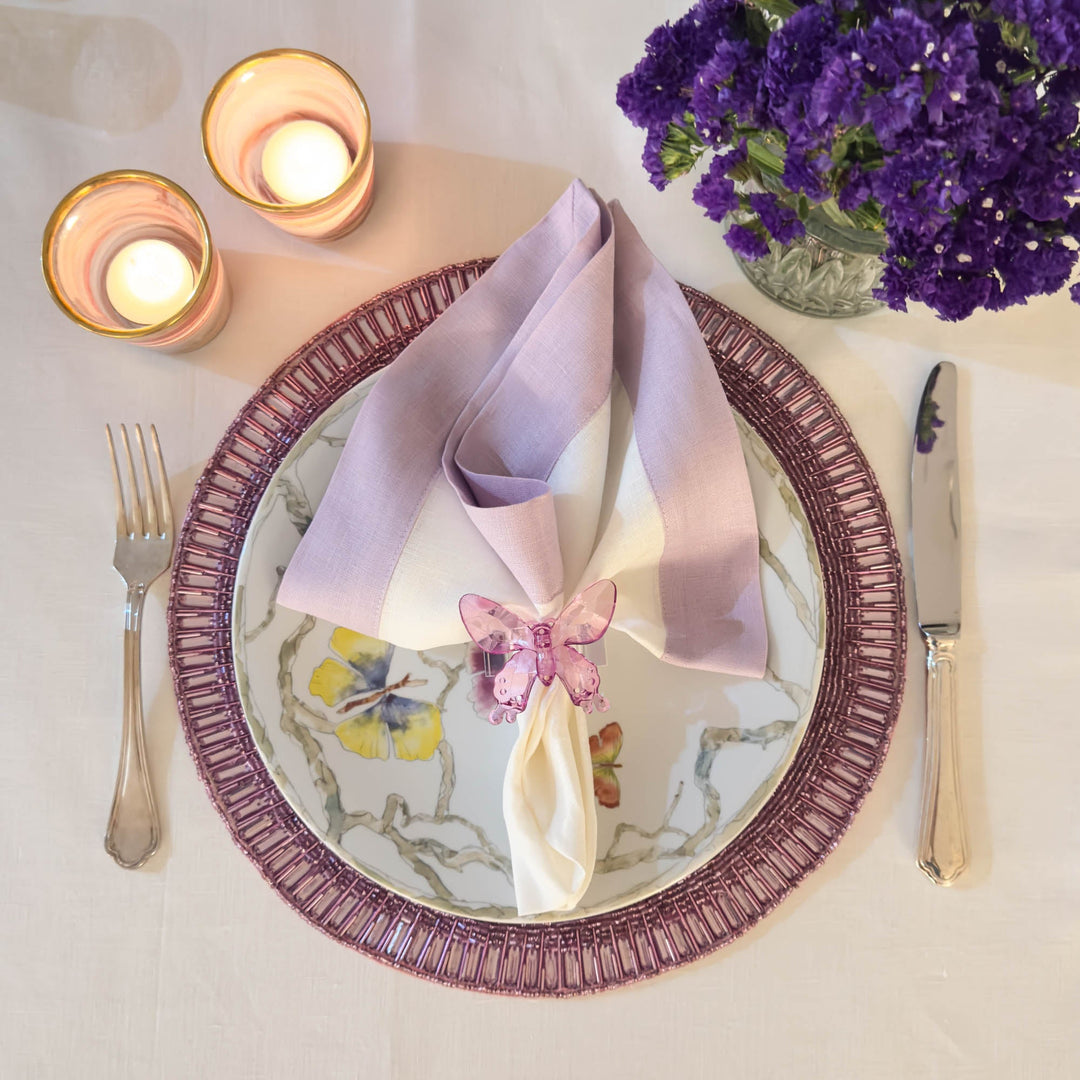 Set of lilac linen napkins with double-sided border, folded and stacked at table