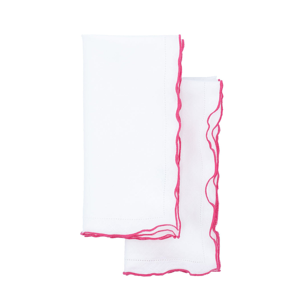 Two folded white linen napkins showing pink ruffled hemstitch edges