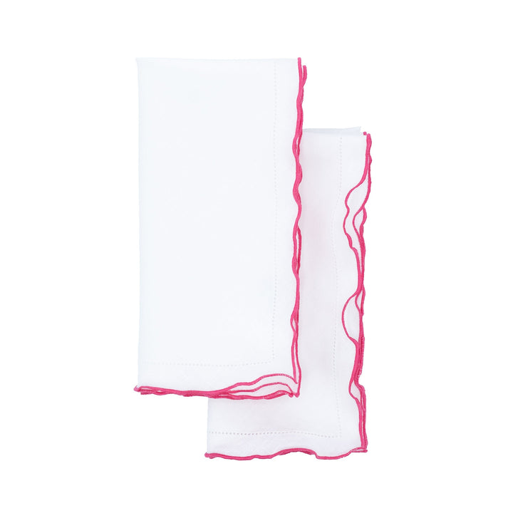 Two folded white linen napkins showing pink ruffled hemstitch edges