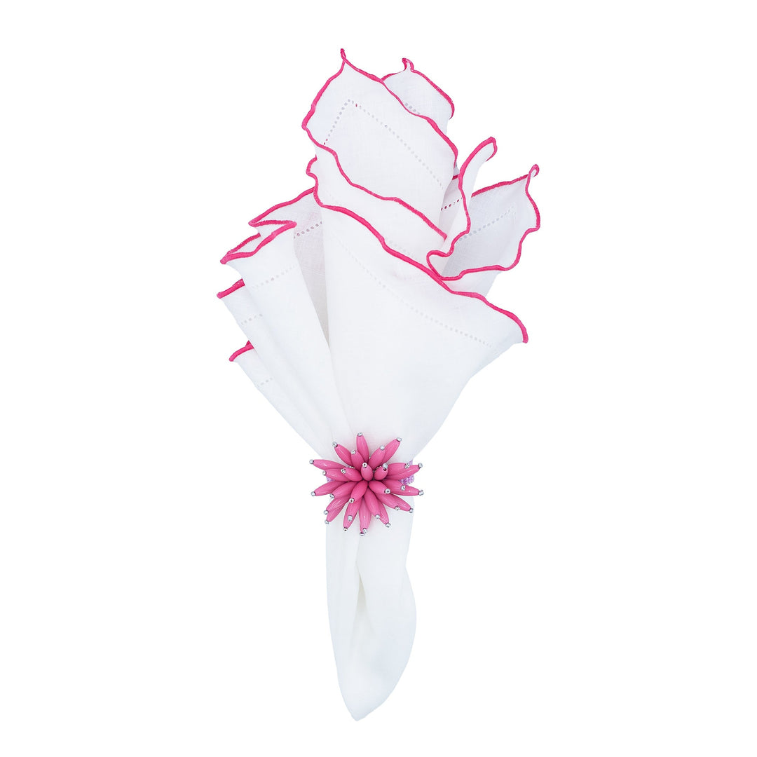 Folded white linen napkin with pink ruffled hemstitch edges tied with a flower