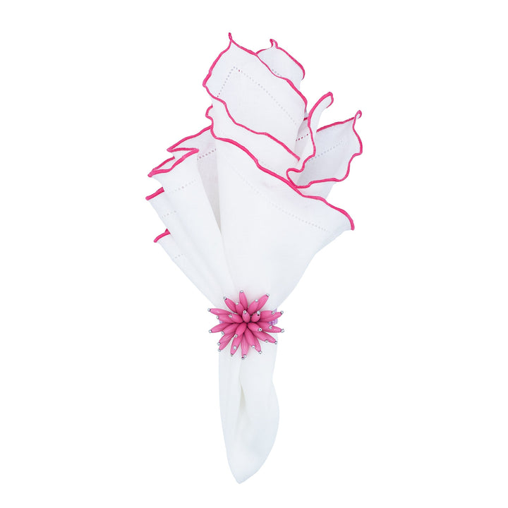 Folded white linen napkin with pink ruffled hemstitch edges tied with a flower