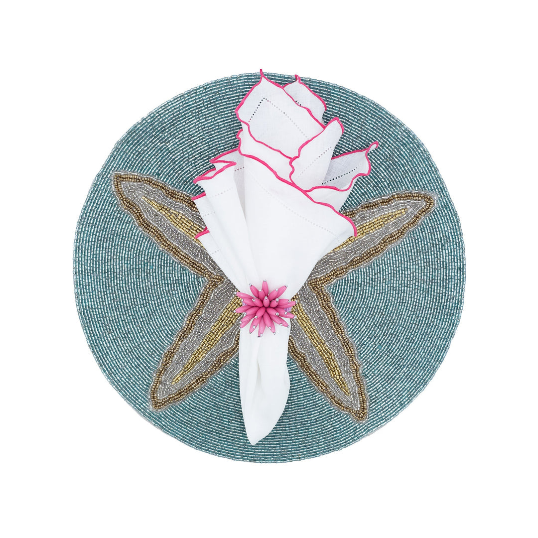 White linen napkin with pink ruffled hemstitch edges on a teal woven plate