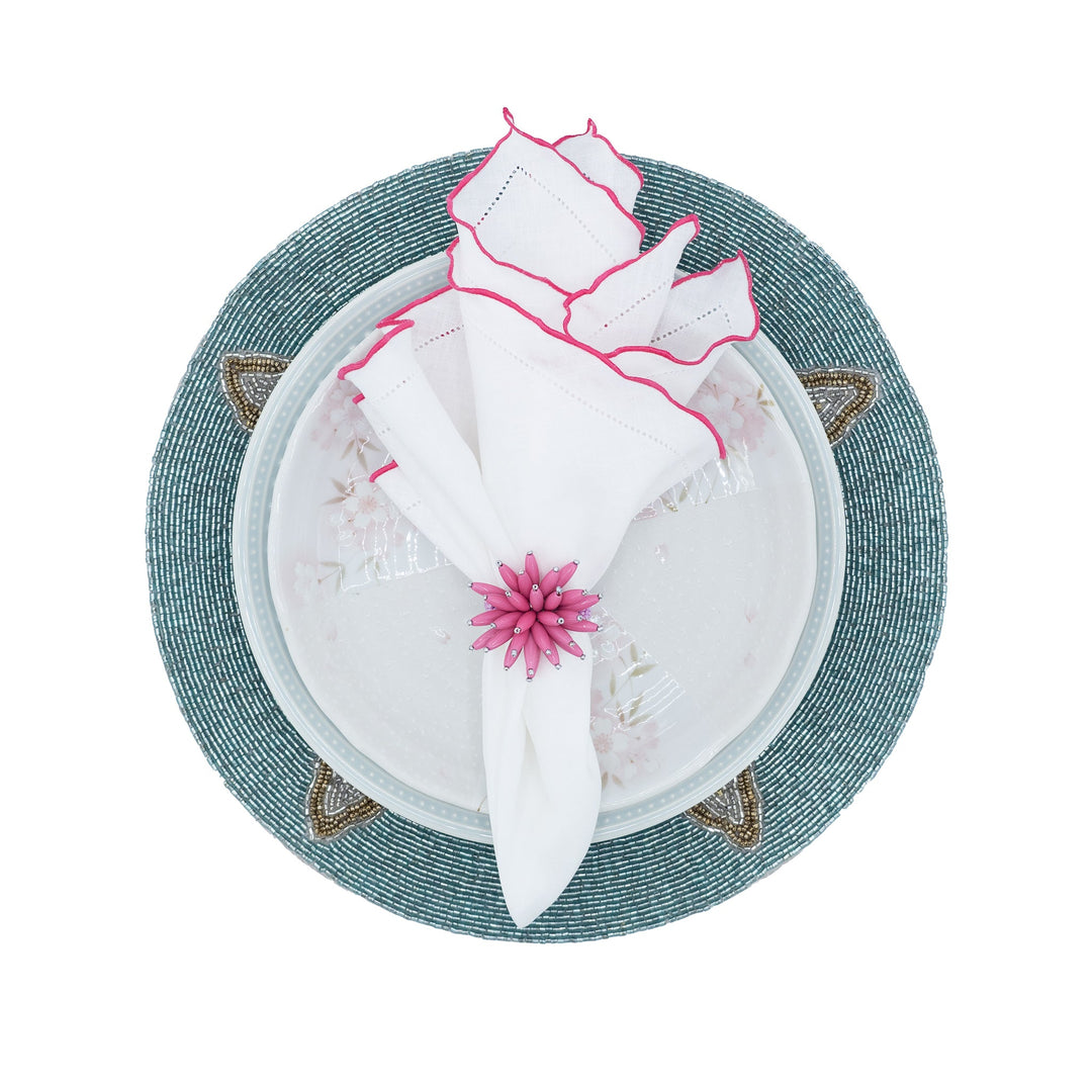 Set of white linen napkins with pink ruffled hemstitch edges on a woven plate