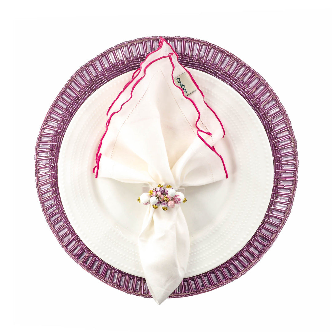White linen napkins with pink ruffled hemstitch edges, folded on a plate