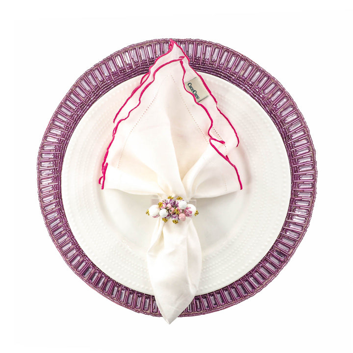 White linen napkins with pink ruffled hemstitch edges, folded on a plate