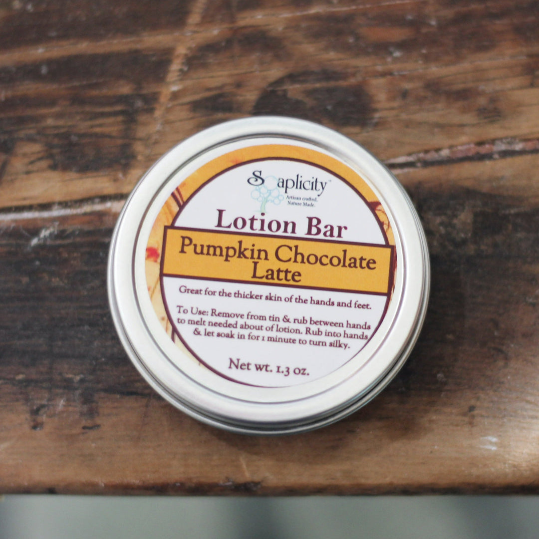 Pumpkin latte lotion bar tin with label, closed metal lid on wooden surface.