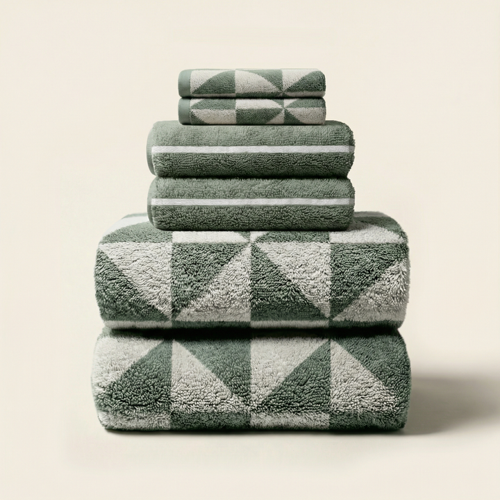 Stacked sage green and ecru patterned cotton towels with geometric blocks