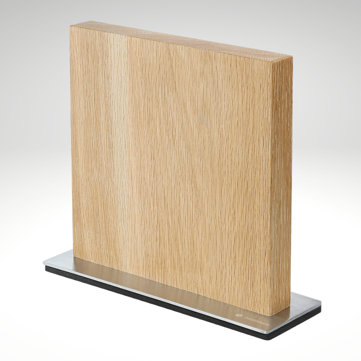 Light wood magnetic knife block with three knives in vertical slots on a black base