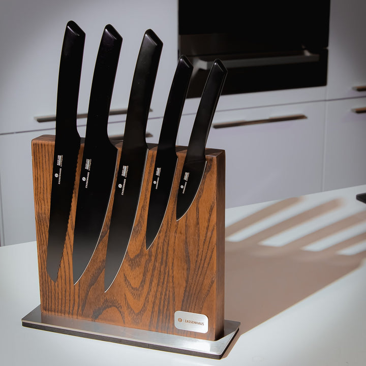 Wood magnetic knife block holding five knives in vertical slots on a black stand