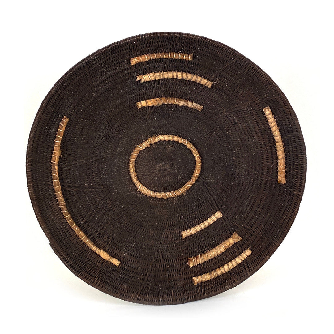 Small woven basket, dark brown with tan stitched arc lines and a central ring motif