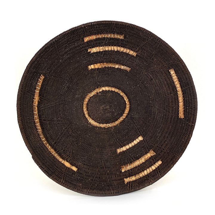 Small woven basket, dark brown with tan stitched arc lines and a central ring motif
