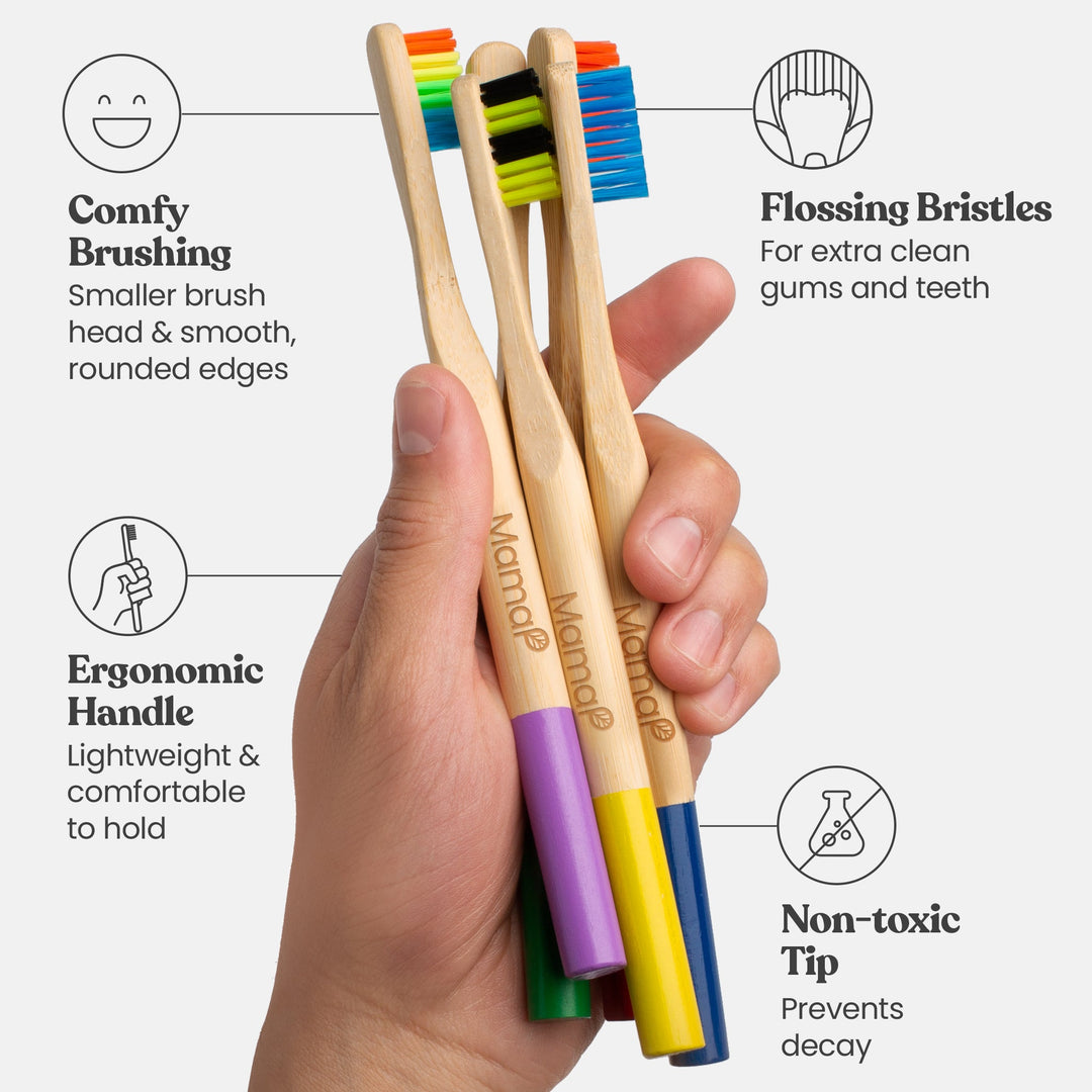 Set of bamboo toothbrushes with colored bristle tips held in hand on natural handles