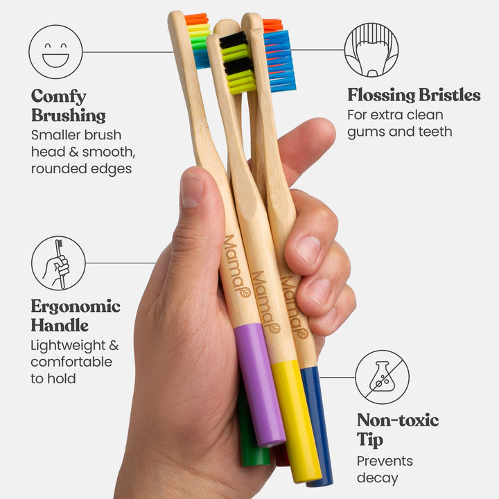Set of bamboo toothbrushes with colored bristle tips held in hand on natural handles
