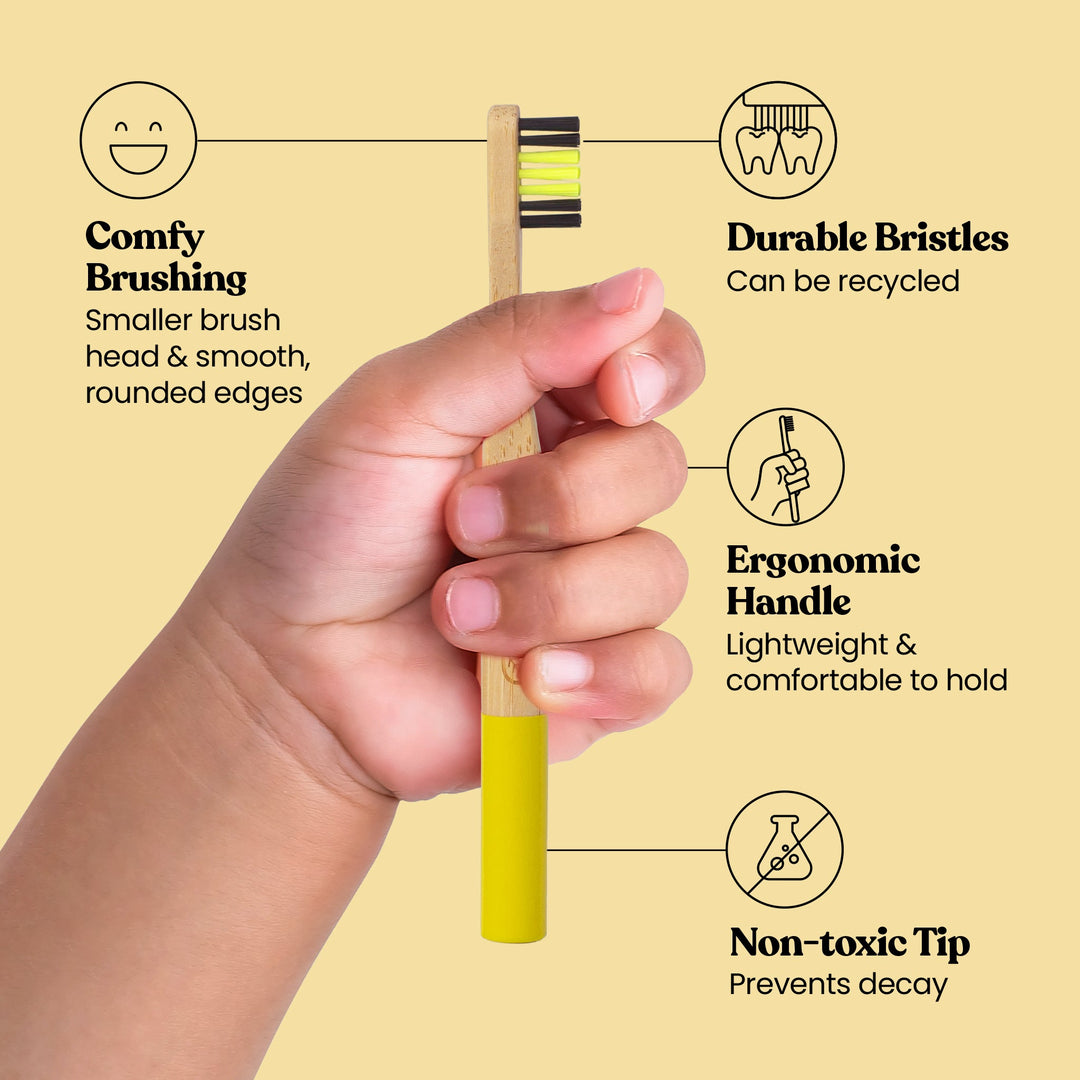 Bamboo toothbrush held in hand; soft yellow bristles and rounded ergonomic handle