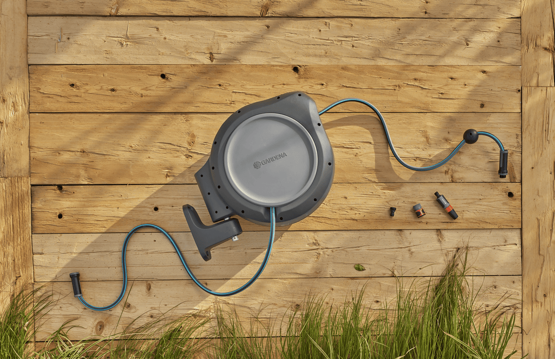 Wall-mounted retractable hose reel with blue hose connected to nozzles and adapters