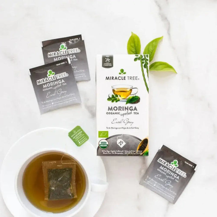 Organic moringa Earl Grey tea boxes with a cup of brewed tea and tea sachets