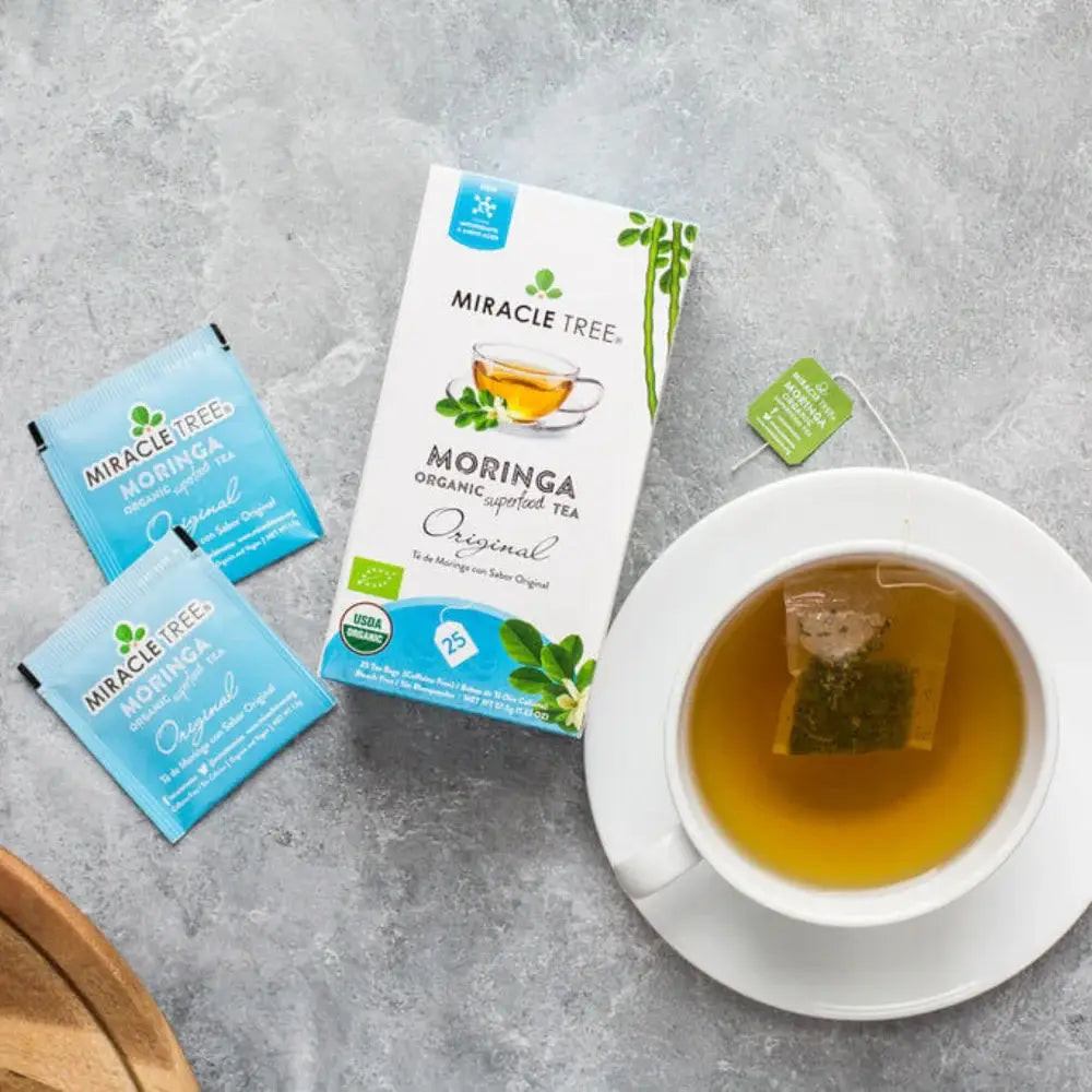 Tea cup beside Miracle Tree Moringa Original tea sachets in blue packs