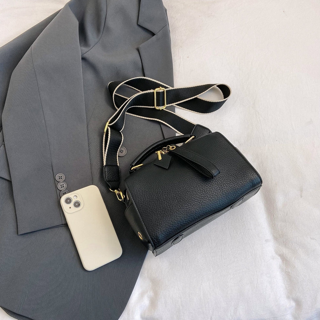 Black mini barrel bag with crossbody strap and gold buckle hardware