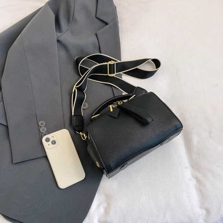 Black mini barrel bag with crossbody strap and gold buckle hardware