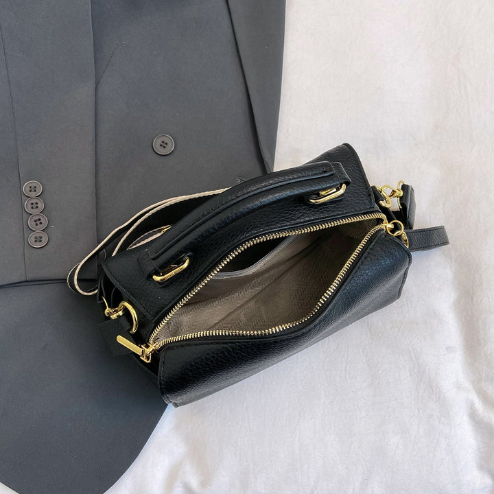 Black mini barrel bag with front zipper, multiple pockets, and gold-tone hardware