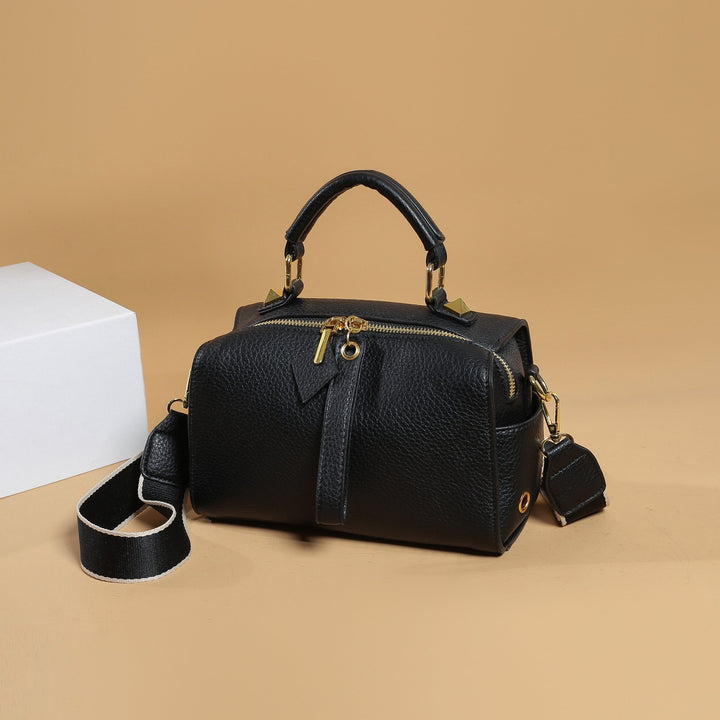 Black mini barrel bag with structured shape, top handle, and crossbody strap