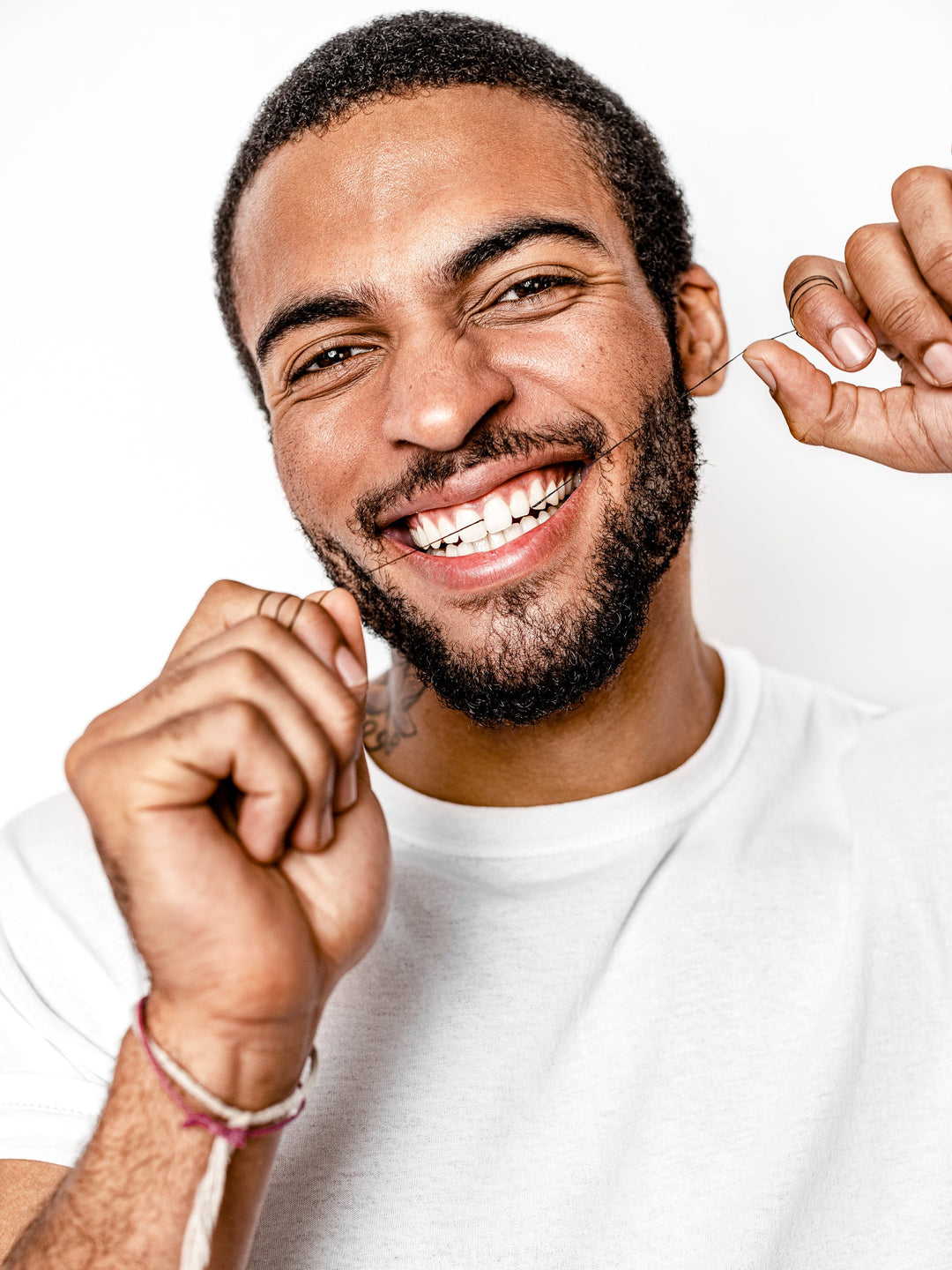 Man holding a floss thread near his smile, using charcoal dental floss