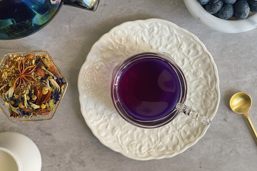 Glass cup of deep purple berry tea on a white plate