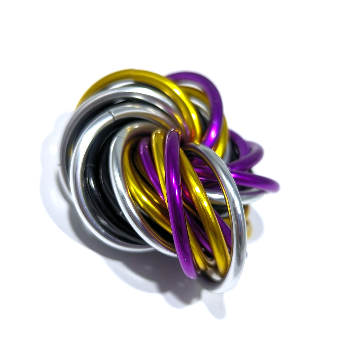 Shiny multicolor fidget stress ball with metallic black, silver, yellow, and purple rings.