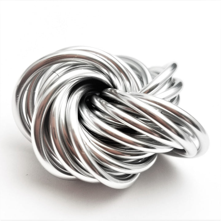 Swirled metallic fidget stress ball, bright silver glossy loops with a long curved strand