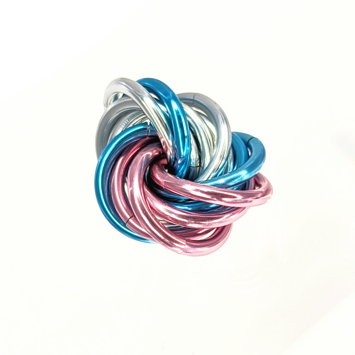 Shiny multicolor fidget stress ball with metallic teal, blue, pink, and silver rings.