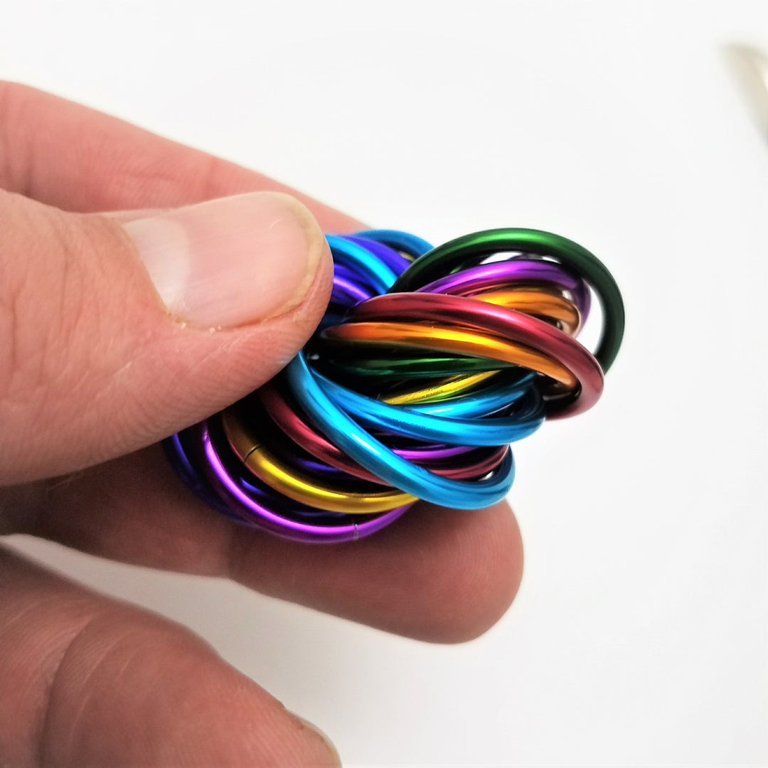 Shiny multicolor ring fidget stress ball held in a hand, tight rainbow swirl