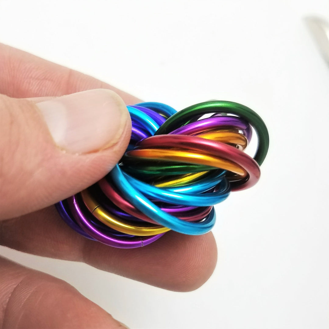 Shiny multicolor ring fidget stress ball in a hand, glossy rainbow rings close-up